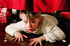 Young Boy in White Sweater Crawling Under Red Curtain