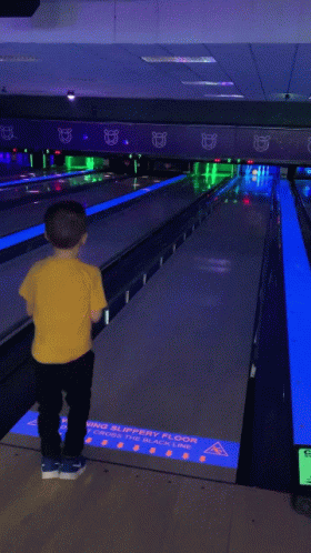 Young Boy in Yellow Shirt With Truck Playing Bowling