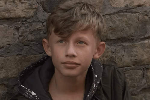 Young Boy Leaning Against Stone Wall Looking at Camera