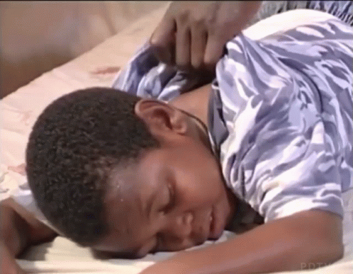Young Boy Lying on Bed with Hand on Neck
