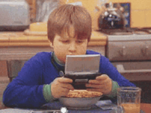 Young Boy Playing Video Game With Cereal And Orange Juice GIF