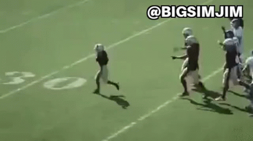 Young Boy Running on Football Field With Players