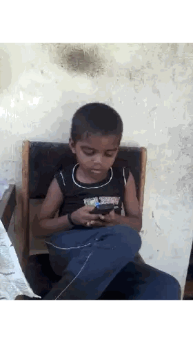 Young Boy Sitting in Chair Looking at Phone
