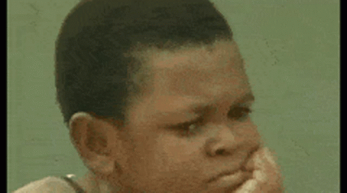Young Boy Sitting On Rock At Beach Looking At Camera GIF