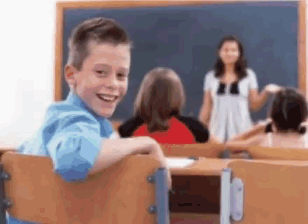 Young Boy Smiling in Classroom with Teacher