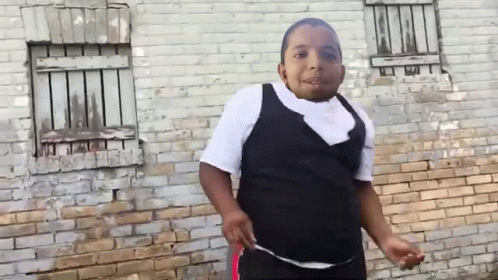 Young Boy Standing in Front of Brick Wall