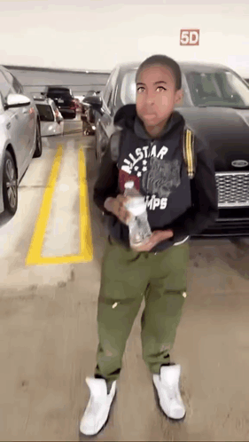 Young Boy Standing in Parking Garage With Bottle of Water