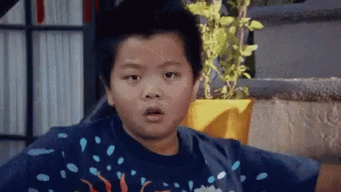Young Boy Surprised Beside Potted Plant