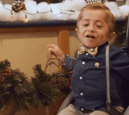 Young Boy With Bow Tie And Suspenders In Chair GIF