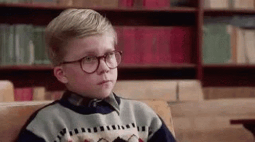 Young Boy With Glasses Sitting on Couch in Front of Bookshelf