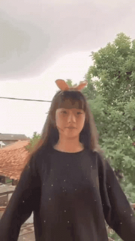 Young Girl in Black Sweater With Bunny Ears Standing in Front of Tree