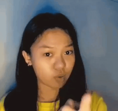 Young Girl in Yellow Shirt Pointing with Funny Face