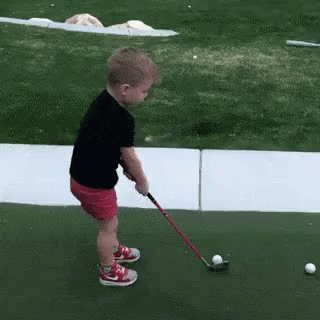 Young Girl Swinging Golf Club at Ball