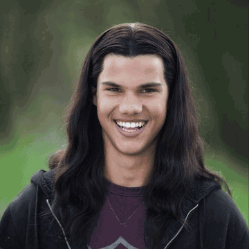Young Long Dark-Haired Man Smiling in Black Hoodie