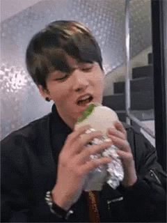 Young Man Eating Foil-Wrapped Hamburger