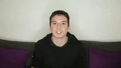 Young Man in Black Hoodie with Funny Face on Purple Couch