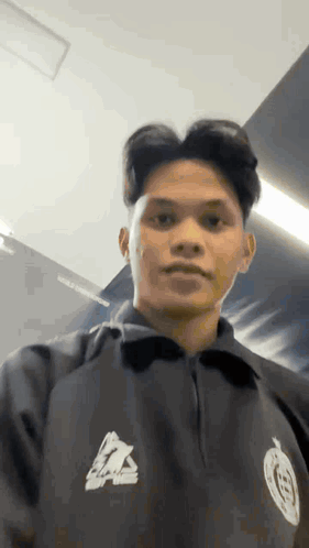 Young Man In Black Jacket Standing By Wall GIF