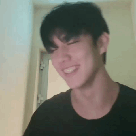 Young Man In Black Shirt Making Funny Face In Front Of Door GIF