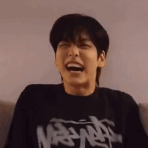 Young Man in Black T-Shirt Laughing on Couch