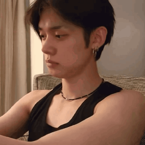 Young Man in Black Tank Top and Earrings Sitting on Couch