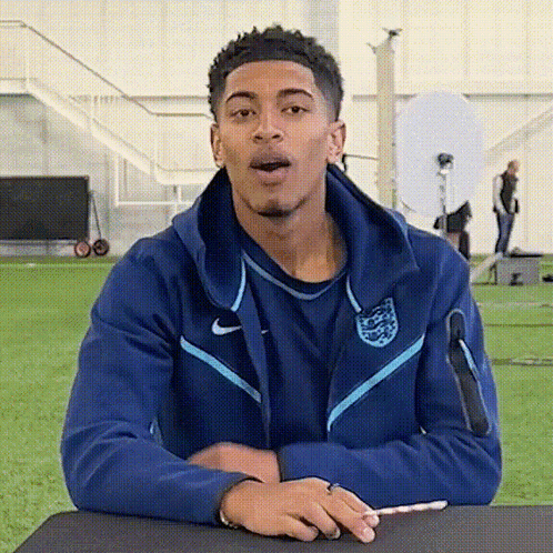 Young Man in Blue Nike Jacket Sitting at Table