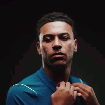Young Man in Blue Shirt Adjusting Tie