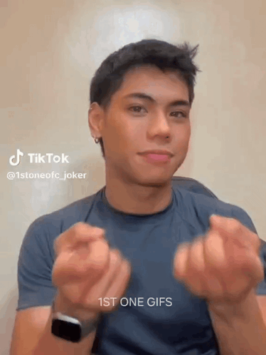 Young Man in Blue Shirt Making Heart Shape with Watch