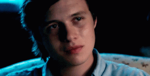Young Man In Blue Shirt Sitting In Darkness GIF