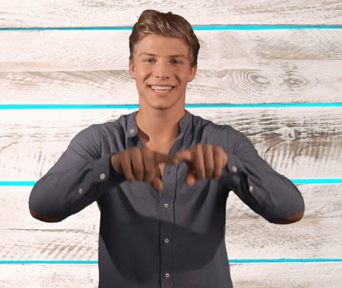 Young Man in Blue Shirt Smiling Making Heart Shape