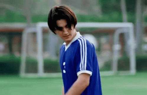 Young Man in Blue Soccer Jersey Standing on Field