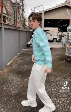 Young Man in Blue Sweater and White Pants on Sidewalk