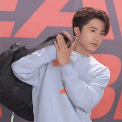 Young Man in Blue Sweater Holding Black Bag