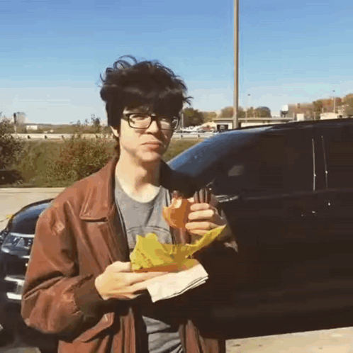 Young Man in Brown Jacket Eating Sandwich
