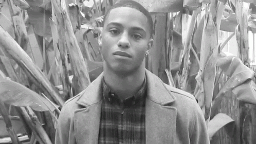 Young Man In Coat And Plaid Shirt By Tree GIF