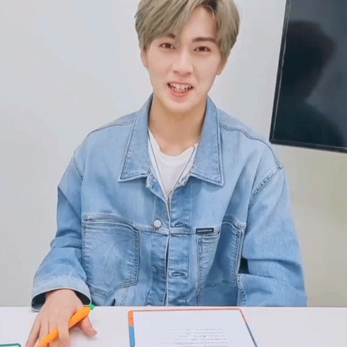 Young Man In Denim Jacket Sitting At Table GIF