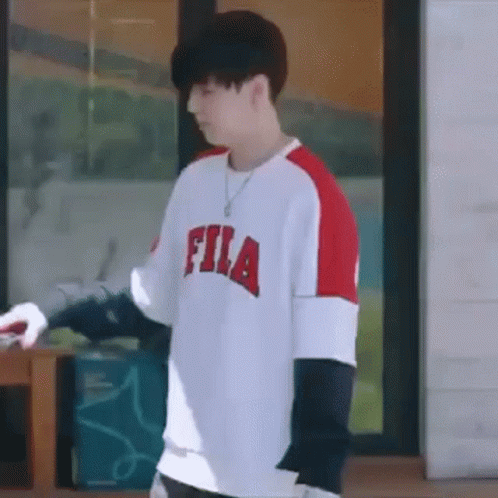 Young Man In Fila Shirt Standing In Front Of Window GIF