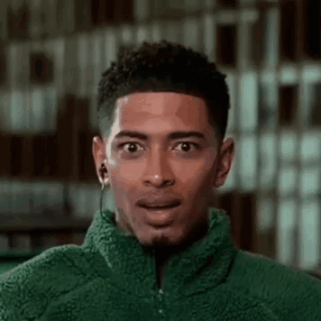 Young Man in Green Jacket With Earbuds Surprised