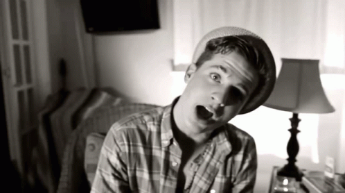 Young Man in Plaid Shirt and Hat in Front of Lamp