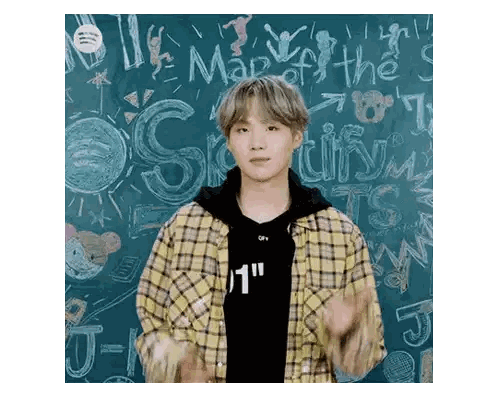 Young Man in Plaid Shirt Standing in Front of Spotify Blackboard
