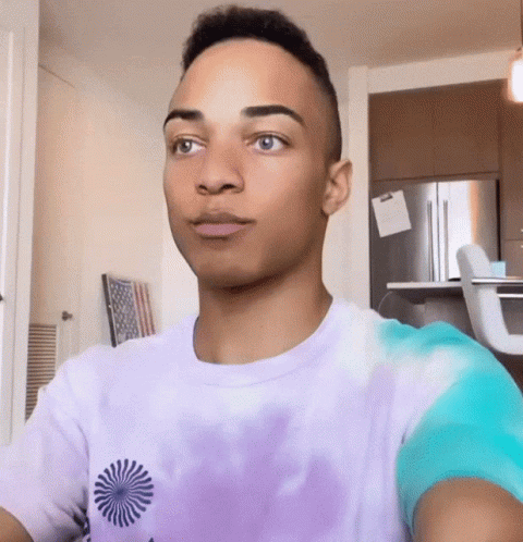 Young Man In Purple Tie Dye Shirt Looking At Camera GIF