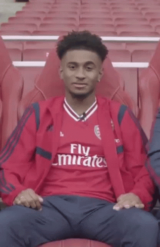 Young Man in Red Emirates Shirt Pointing