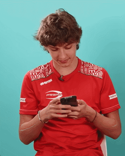 Young Man in Red Errea Shirt Looking at Phone