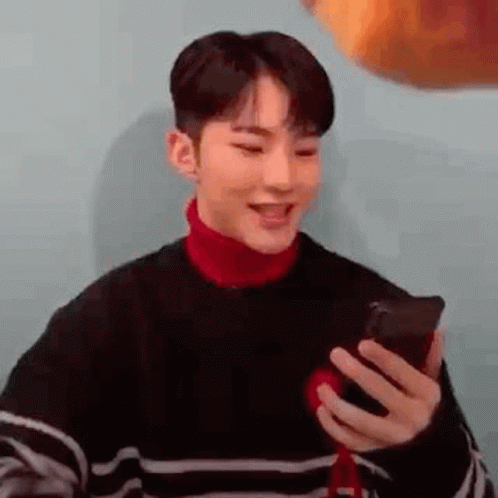 Young Man in Striped Sweater Holding Cell Phone