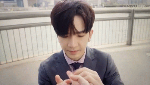 Young Man In Suit Holding Small Object GIF