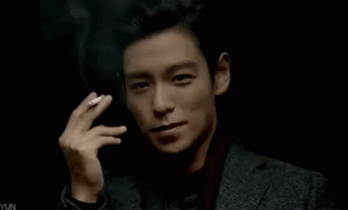 Young Man in Suit Smoking Cigarette in Dark Room