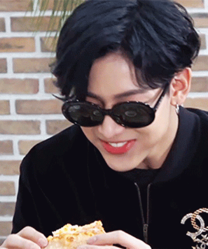 Young Man in Sunglasses and Black Jacket Eating Pizza