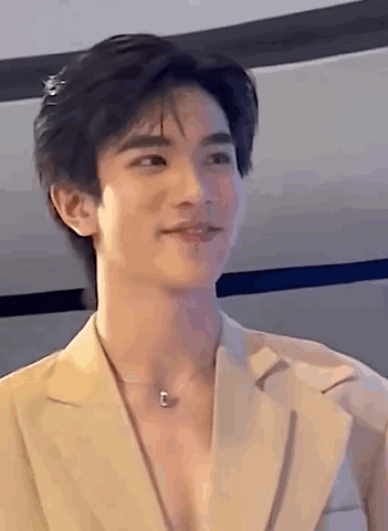 Young Man in Tan Jacket and Necklace Smiling