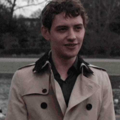 Young Man in Trench Coat and Black Shirt Smiling