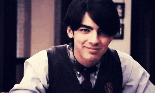 Young Man In Vest And Tie With M Badge GIF