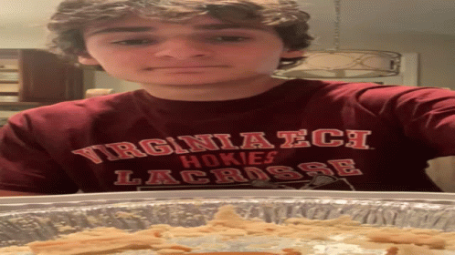 Young Man in Virginia Tech Shirt Standing by Pan of Food